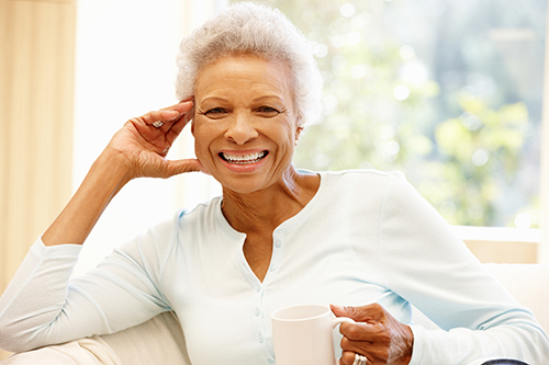 African american woman with short hair smiling and holding a coffee cup